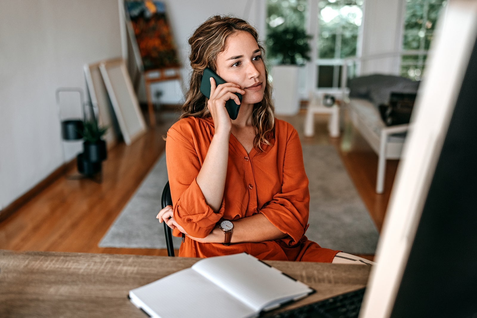 Young woman talking on smart phone at home office